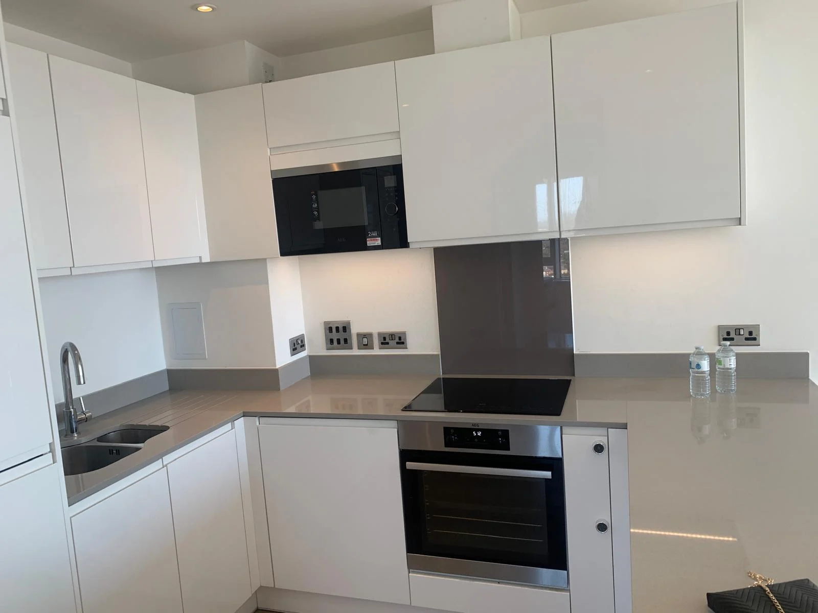 Modern kitchen with white cabinets, oven, and clean worktops after service.